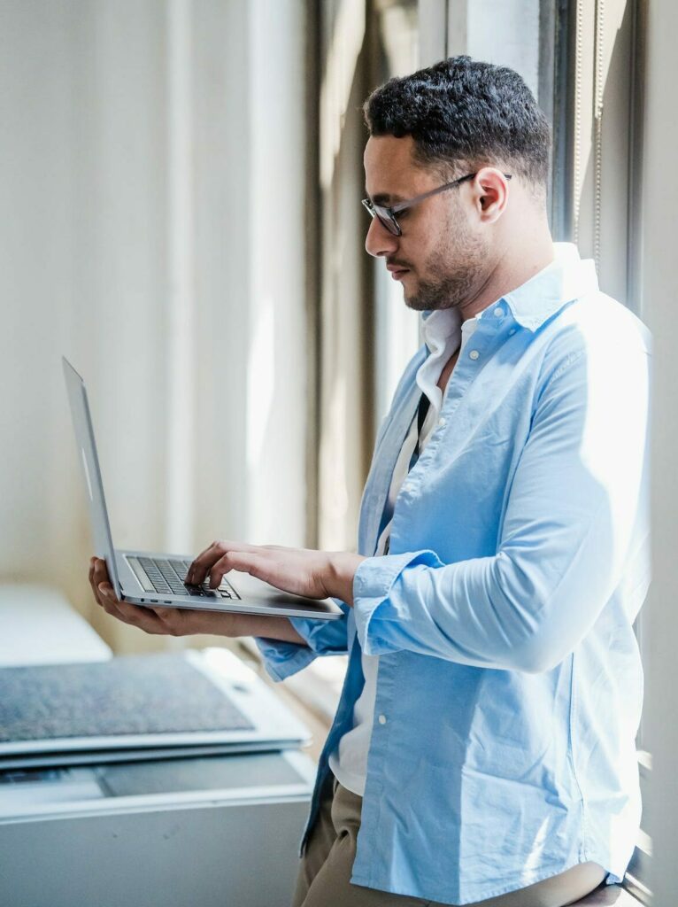 ethnic man sideways focused and working on laptop