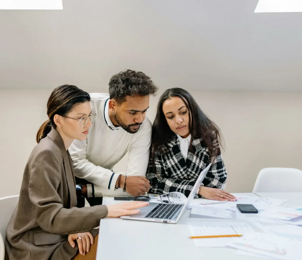 A group of people looking at a laptop and reviewing Form 1120-s instructions.